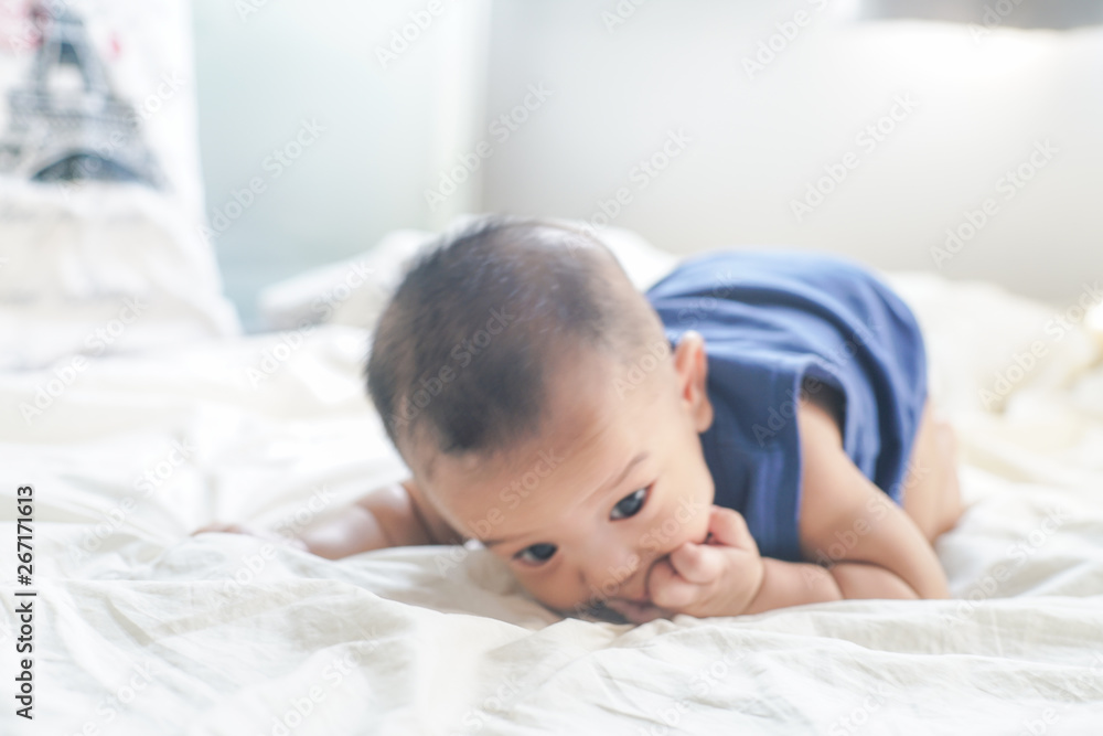 Adorable baby boy sucking finger lying on bed Adorable baby boy sucking finger lying on bed