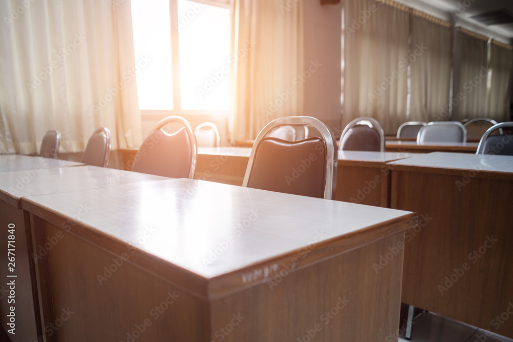 Education concept: Empty college or university classroom with wooden tables and chairs in row without student or teacher in the room. School classroom with window opened, clean and tidy ready for new 