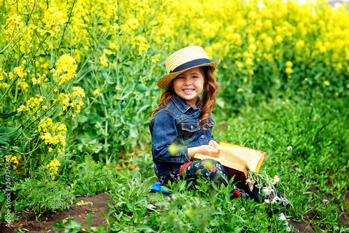 Portrait of a pretty girl in a field with a book . The concept of pre-school education