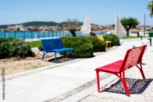 Small Red Bench Overlooking the Aegean Sea on Blue Sky Background.