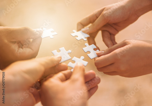 Hands holding piece of blank jigsaw puzzle for teamwork workplace success and strategy concept