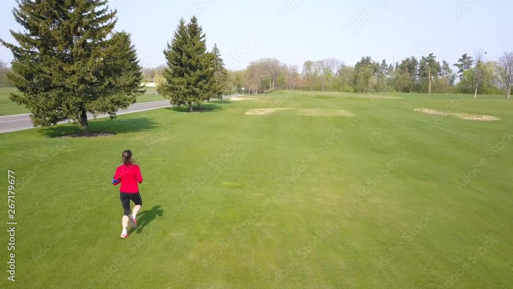 4K. Healthy aerial team .Woman fitness runner in red run on green field. 4K. Healthy aerial team .Woman fitness runner in red run on green field.