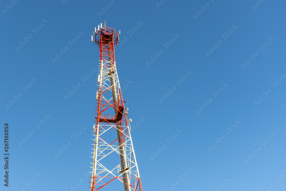 A red and white mobile or cell phone telecommunications tower on a blue sky background looking up. A red and white mobile or cell phone telecommunications tower on a blue sky background looking up.