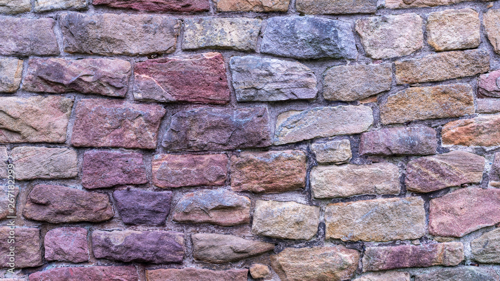 Fototapeta premium Stone texture. Colorful rock wall. Wall of colored stones bonded with cement.