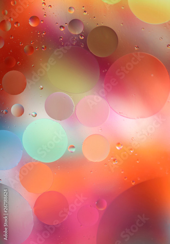 Oil drops in water on a colored background. Bright background with pink, orange and green circles of different sizes. Blur, vertical, place for text, multi-color. Concept of design.