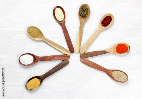 Assortment of spices in wooden spoons, white background