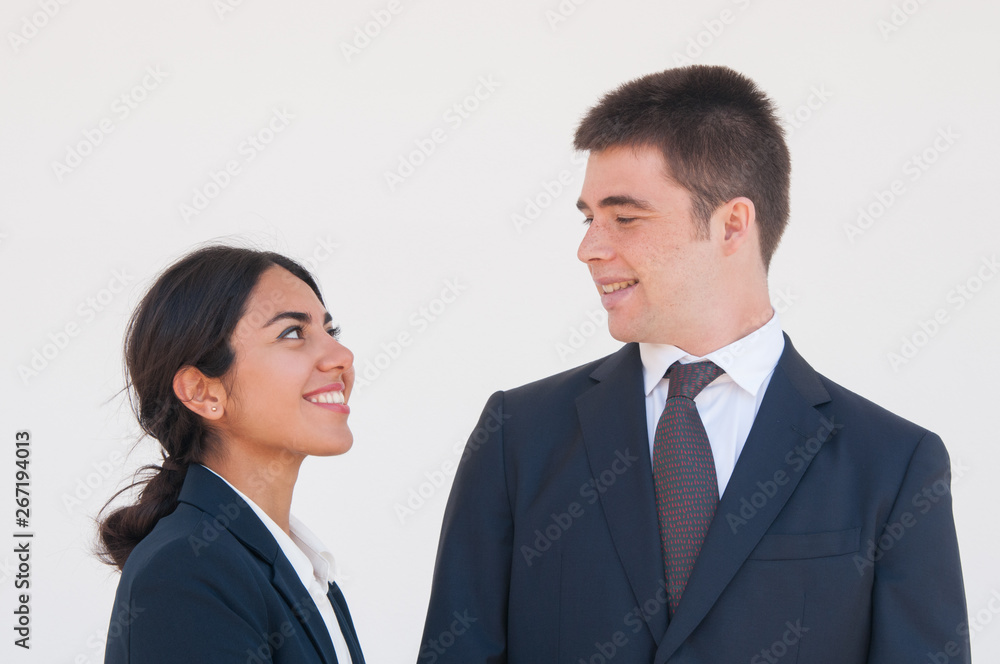 Happy cheerful coworkers enjoying nice talk. Young man and woman in formal suits smiling at each other and flirting. Corporate dating concept Happy cheerful coworkers enjoying nice talk. Young man and woman in formal suits smiling at each other and flirting. Corporate dating concept