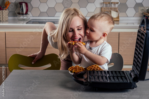 caucasian family together cooking kitchen.boy and mother eating Belgian waffles waffle iron photo