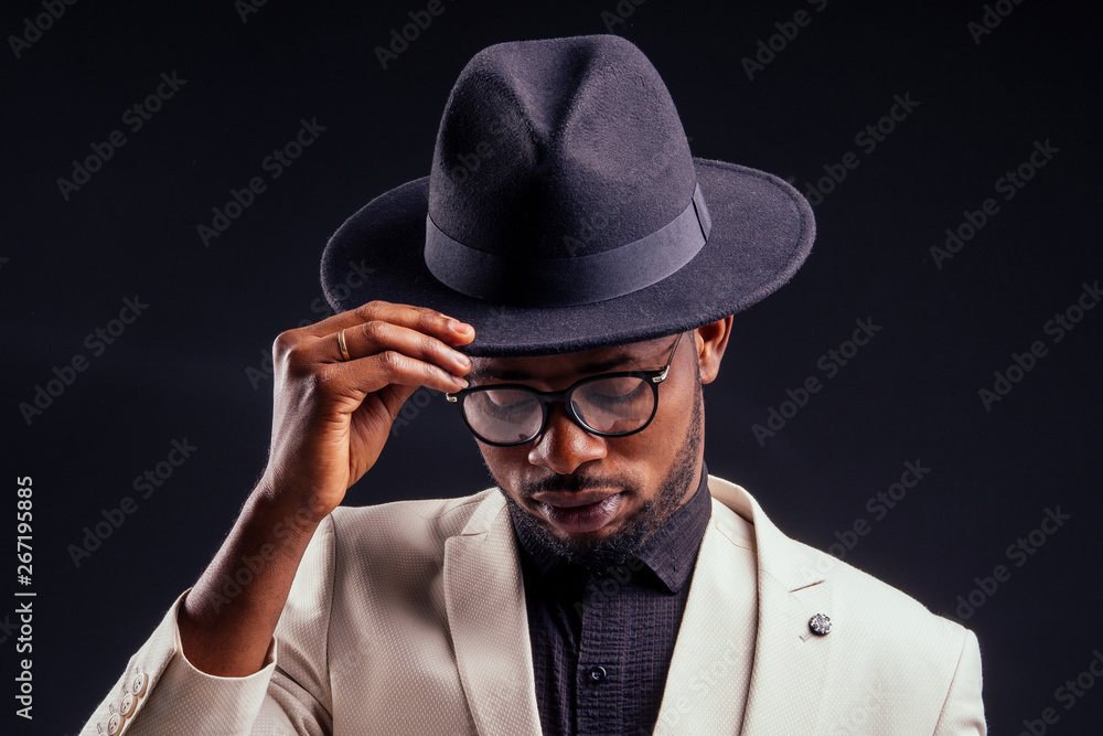 young handsome afro american melancholy boy in a white jacket and glasses on a black background in the studio.mystery and grief young handsome afro american melancholy boy in a white jacket and glasses on a black background in the studio.mystery and grief