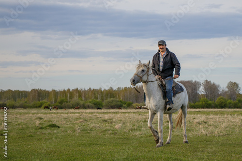  A fermer on a white horse in the field © IrinaK