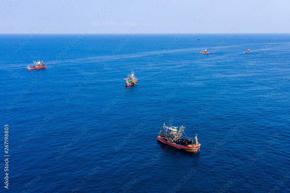 Aerial drone view of a fleet of industrial fishing trawlers in a tropical ocean