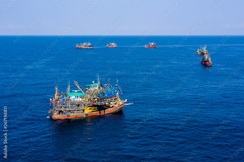 Industrial overfishing - Aerial view of a SCUBA diving boat and a fleet of large fishin trawlers near a small rocky island (Black Rock, Mergui, Myanmar)