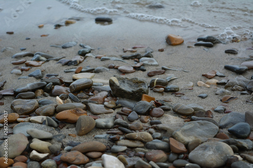 Pebble stones on the sandy shore of river. Closeup.