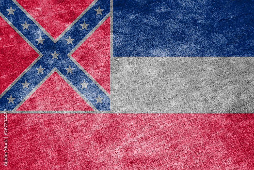 The national flag of the US state Mississippi in against a gray textile rag on the day of independence in different colors of blue red and yellow. Political and religious disputes, customs and delive The national flag of the US state Mississippi in against a gray textile rag on the day of independence in different colors of blue red and yellow. Political and religious disputes, customs and delive