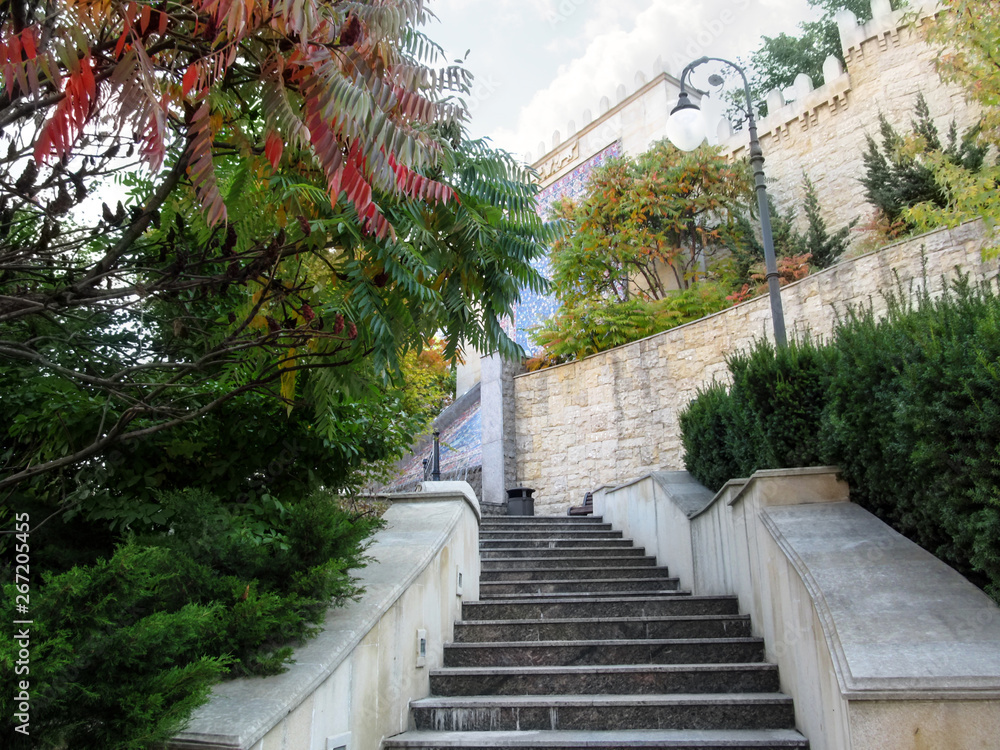 Kiev, Ukraine - October 8, 2018: Staircase leading to fountain-waterfall in Heydar Aliyev Park (Kiev). Landscape in the Middle Eastern style - granite staircase near a stone wall among exotic greenery