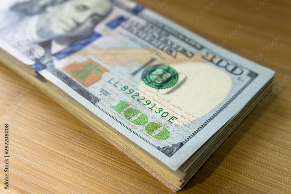 crolled stack of 100 new dollar bills on wooden background crolled stack of 100 new dollar bills on wooden background
