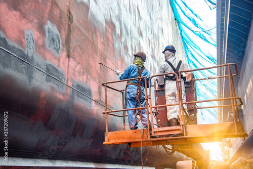 Steel basket carry by cherry picker crane for gang of worker power man, painting man or brush man working in high position, working at risk in dust under mesh sheet protection.