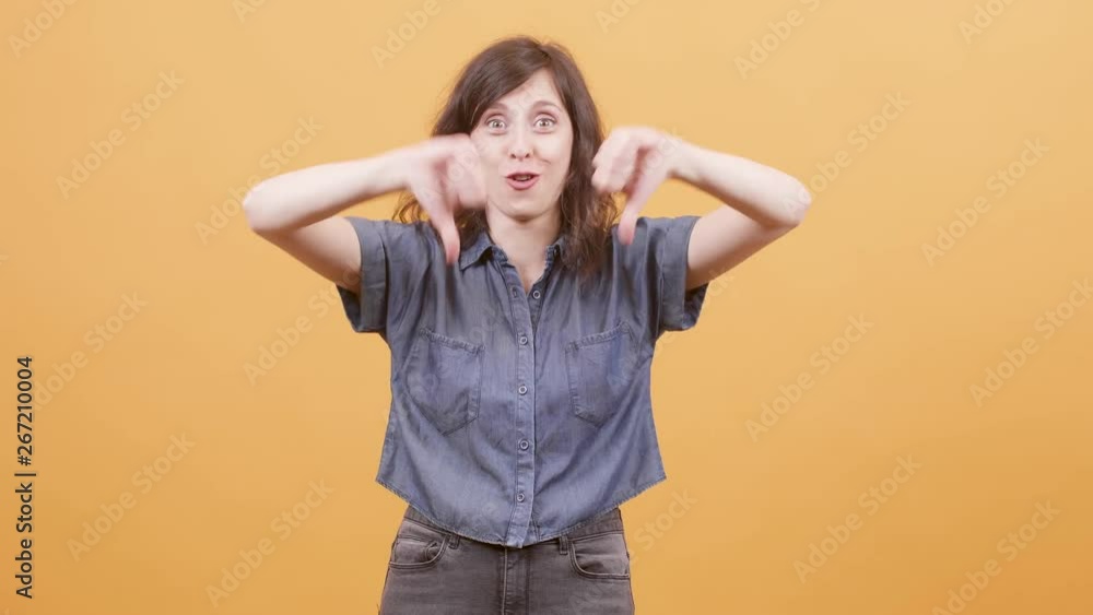 Young woman over yellow background showing thumbs down sign. Dissaproving sign showed by a young female. Young woman over yellow background showing thumbs down sign. Dissaproving sign showed by a young female.
