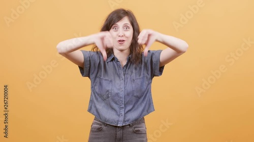 Young woman over yellow background showing thumbs down sign. Dissaproving sign showed by a young female. photo