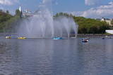 boats with vacationers on the Bay in Cheboksary on the background of the fountain and the historical part of the city,shot on a clear and warm spring day