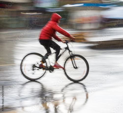 Cyclist on the city roadway in motion blur in rainy day. Intentional motion blur © vbaleha