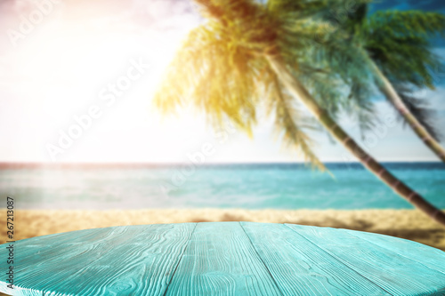 Summer background of wooden table and beach background with palms 