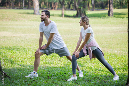 Happy young couple loving fitness in sportswear stretching leg for exercising or running at park together in morning time. sport people . relationships. training , workout