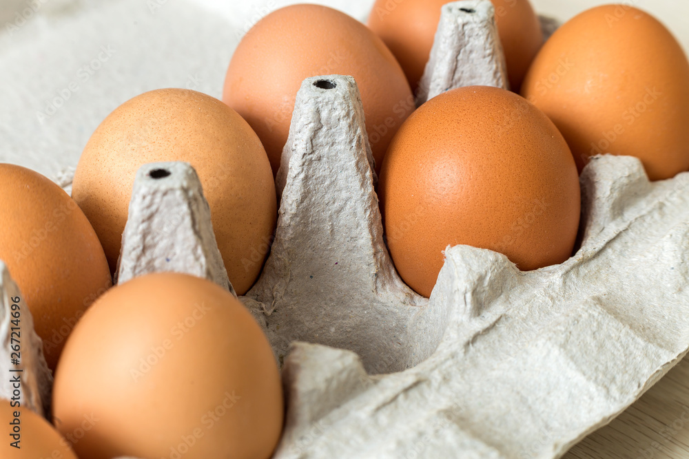 Hen eggs in open cardboard egg carton on kitchen table light copy space background. Healthy organic food and diet concept. Hen eggs in open cardboard egg carton on kitchen table light copy space background. Healthy organic food and diet concept.