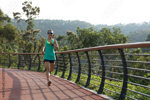Runner athlete running on spring forest trail. woman fitness jogging workout wellness concept.