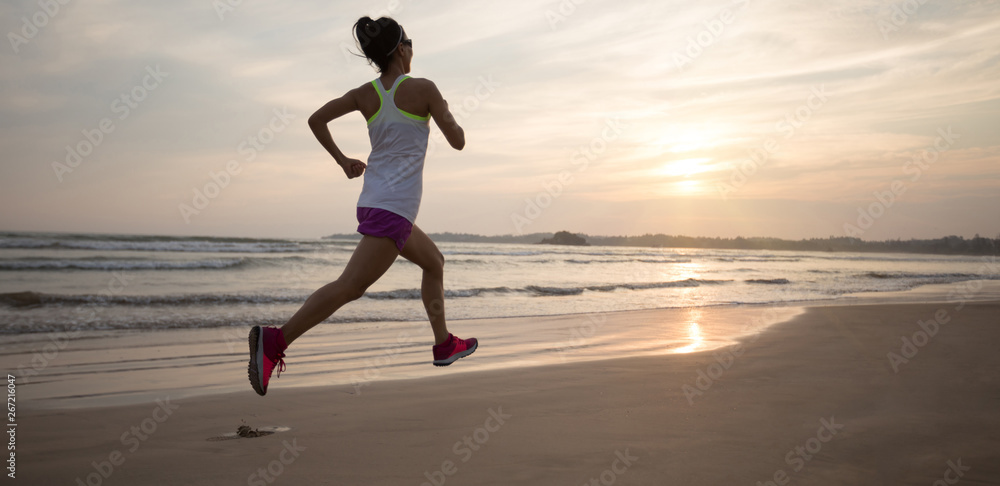 Young fitness woman running at sunrise beach