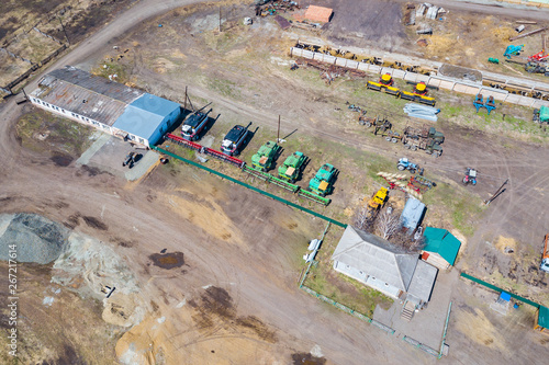 Top view on agricultural machinery near the hangar in the village for planting and harvesting. Tractor, plow, combine fuel truck and truck in green and blue. Agriculture and farming.