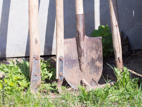 old rusty dirty tools for working in the garden, facing the wall of a barn, farming tools