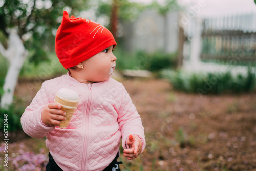 little girl in the garden in a red hat eating ice cream with a Cup
