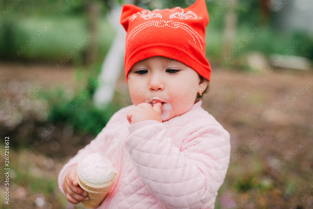 little girl in the garden in a red hat eating ice cream with a Cup little girl in the garden in a red hat eating ice cream with a Cup