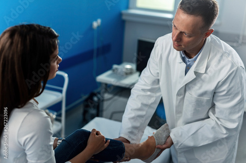 Male orthopedist examining the patient's leg at clinic. photo