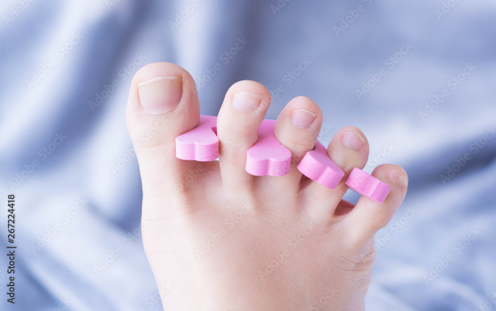 Woman preparing for foot pedicure at home by herself with nail separators Woman preparing for foot pedicure at home by herself with nail separators