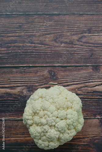 Top view of cauliflower on wooden background. Copy space for text or logo. Vertical shot.