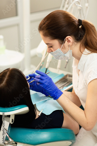 Closeup portrait of young woman patient  sitting in dentist chair. Doctor examines the teeth. Dental health prevention