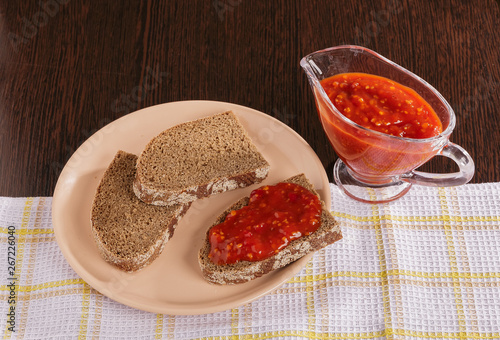 Pieces of rye bread and thick tomato sauce on a plate on the table.