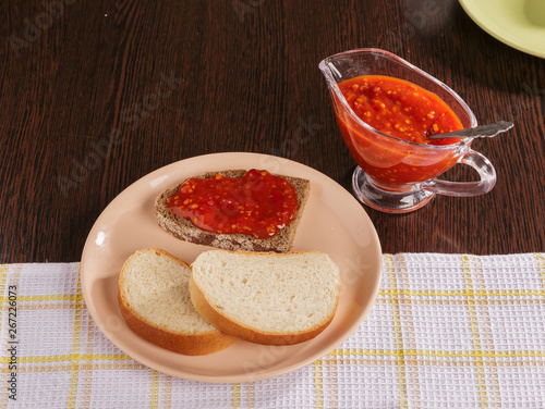 Pieces of rye bread and thick tomato sauce on a plate on the table.