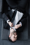 top view of depressed businessman in black suit suffering while lying on sofa