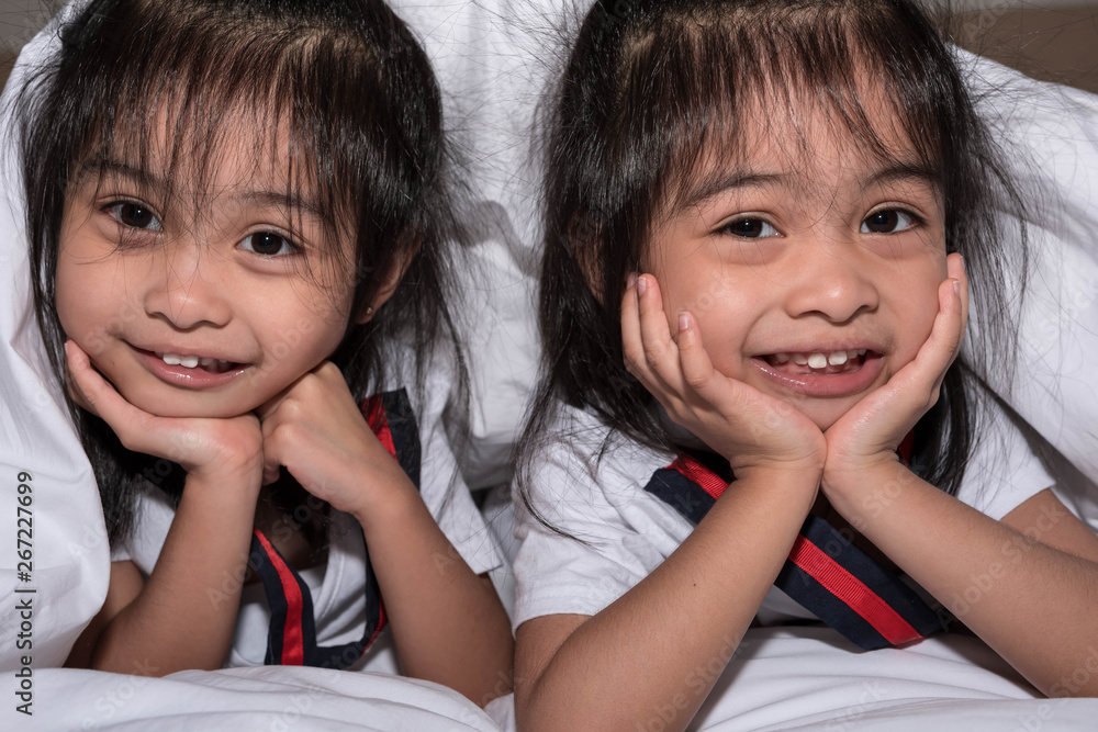 happy little girls twins sister in bed under the blanket having fun, smiling and wacky happy little girls twins sister in bed under the blanket having fun, smiling and wacky
