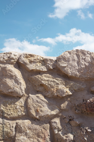 Wall made of stone and rock / Blue sky with white clouds. Warm filter and muted black