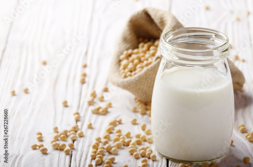 Non-dairy alternative Soy milk or yogurt in mason jar on white wooden table with soybeans in hemp sack