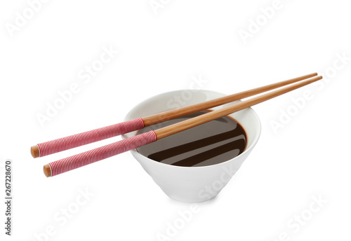 Bowl of soy sauce and chopsticks on white background