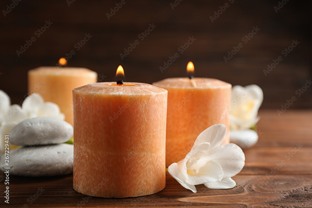 Burning candles, spa stones and flowers on table. Space for text