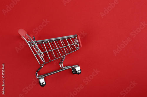 Empty shopping trolley on color background, top view. Space for text