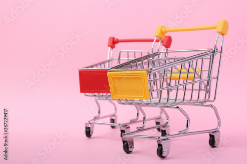 Empty shopping trolleys on color background. Space for text