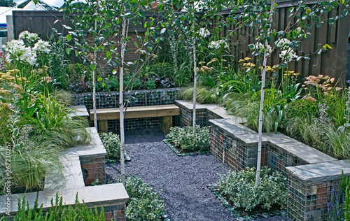A small courtyard garden with seating and mixed planting including Agapanthus, Grasses and Achillea