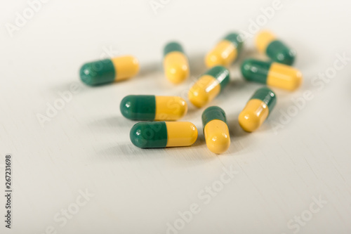 Green, yellow tramadol capsule pills on white background.Pain killer capsules called 